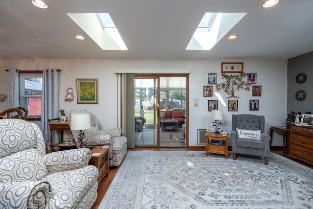 living area with wood finished floors, plenty of natural light, a skylight, and recessed lighting