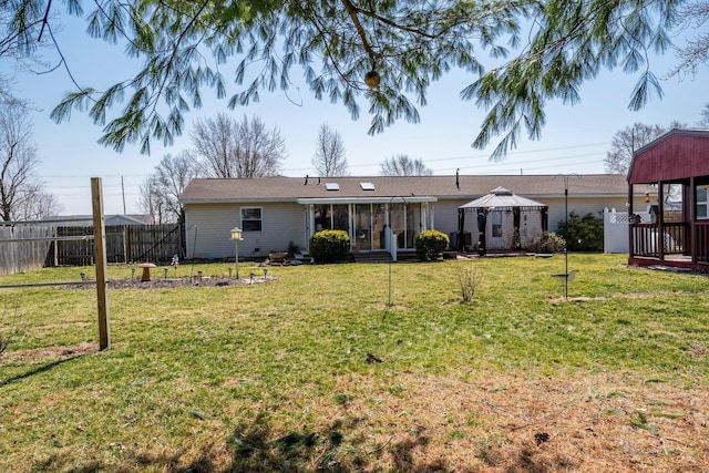 rear view of property with a gazebo, a yard, fence, and a sunroom