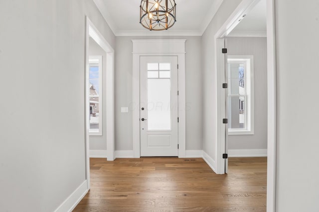 foyer with ornamental molding, baseboards, hardwood / wood-style floors, and an inviting chandelier