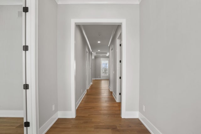 hallway featuring baseboards, wood finished floors, and recessed lighting