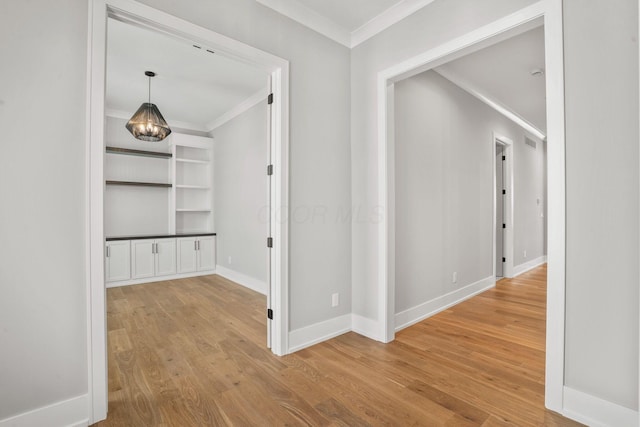 corridor featuring ornamental molding, baseboards, and wood finished floors