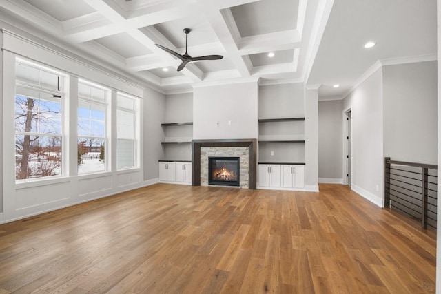 unfurnished living room with light wood finished floors, a stone fireplace, beamed ceiling, and coffered ceiling