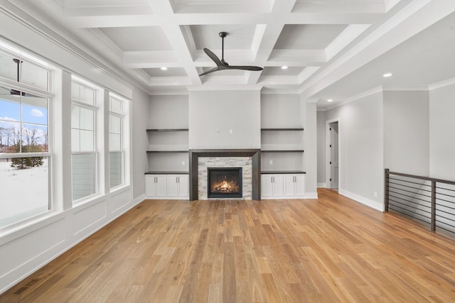 unfurnished living room with light wood-type flooring, baseboards, a fireplace, and beamed ceiling