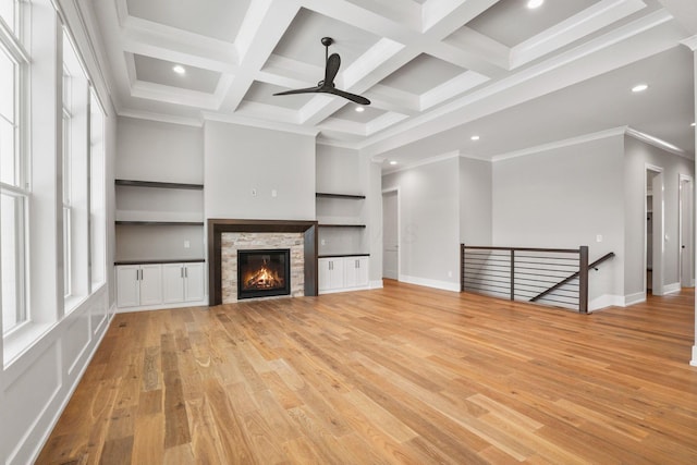 unfurnished living room featuring beam ceiling, light wood finished floors, recessed lighting, a stone fireplace, and coffered ceiling