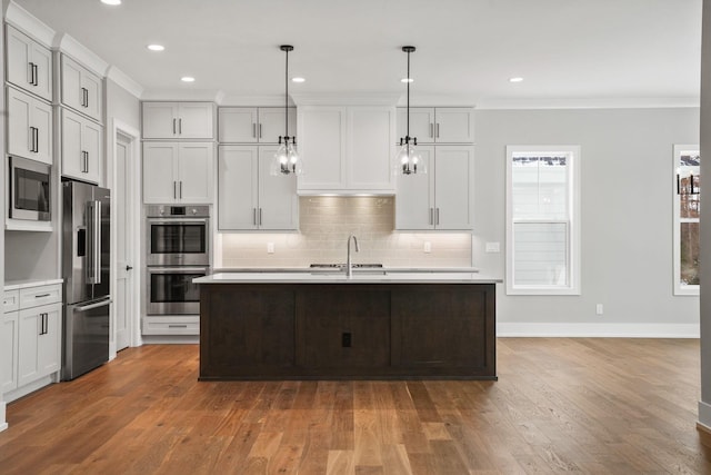 kitchen featuring crown molding, light countertops, decorative backsplash, appliances with stainless steel finishes, and wood finished floors