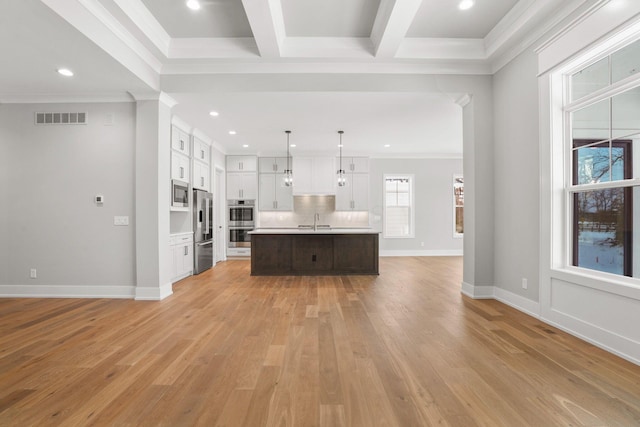 interior space with stainless steel appliances, a sink, visible vents, open floor plan, and light countertops