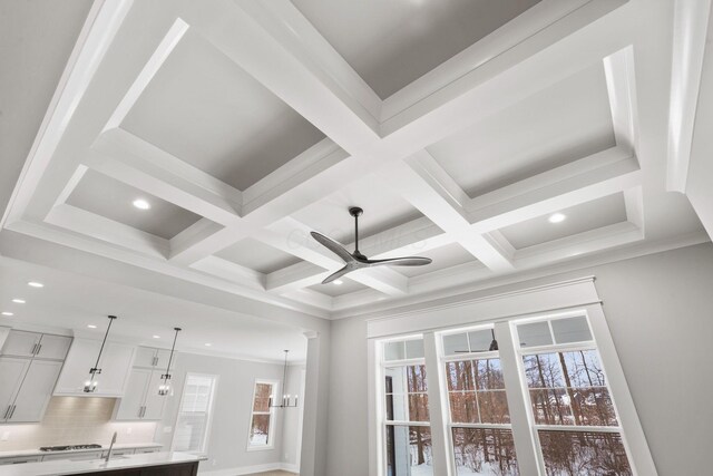 interior details with coffered ceiling, a ceiling fan, beamed ceiling, light countertops, and backsplash