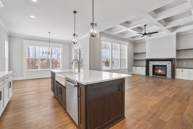 kitchen featuring a sink, light wood-type flooring, stainless steel dishwasher, and beamed ceiling