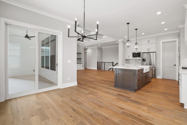 kitchen with appliances with stainless steel finishes, open floor plan, light countertops, and ornamental molding