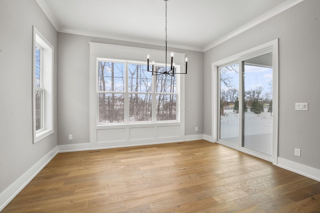 unfurnished dining area featuring hardwood / wood-style flooring, baseboards, ornamental molding, and an inviting chandelier