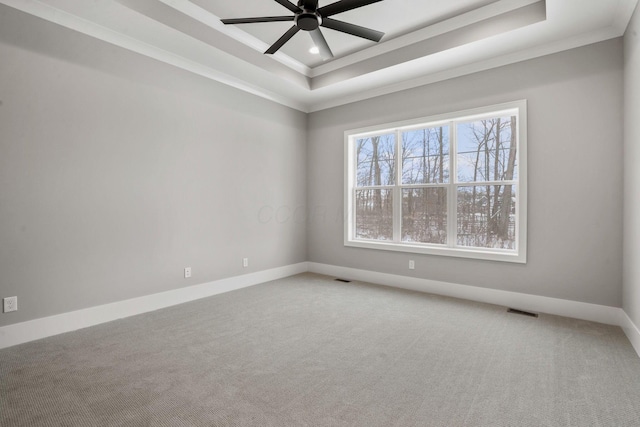 empty room with baseboards, a tray ceiling, carpet, and crown molding