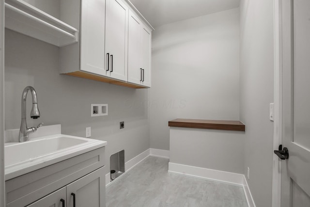 clothes washing area featuring hookup for a washing machine, cabinet space, a sink, electric dryer hookup, and baseboards