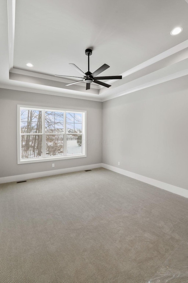 unfurnished room with carpet, a raised ceiling, visible vents, and baseboards