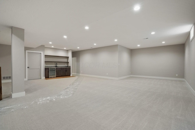 unfurnished living room featuring recessed lighting, light colored carpet, visible vents, beverage cooler, and baseboards