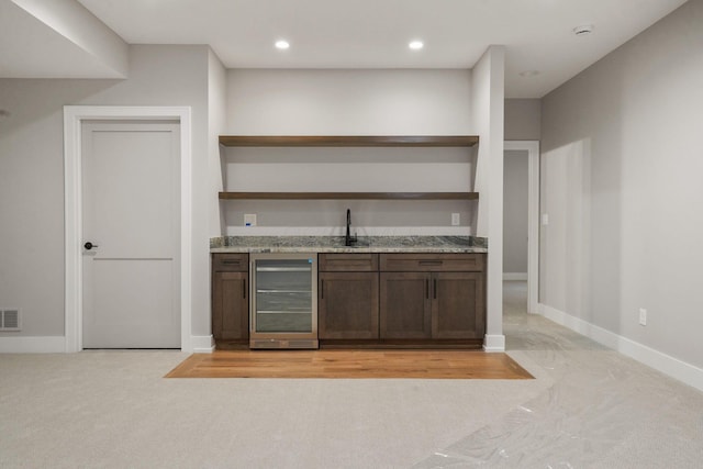 bar with beverage cooler, baseboards, visible vents, and wet bar