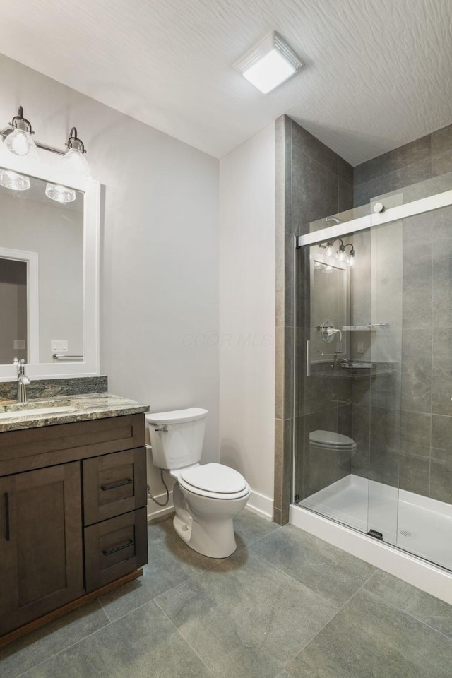 bathroom with toilet, tile patterned floors, a shower stall, and vanity