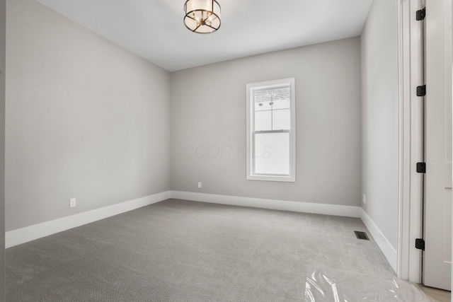 carpeted spare room with baseboards and visible vents