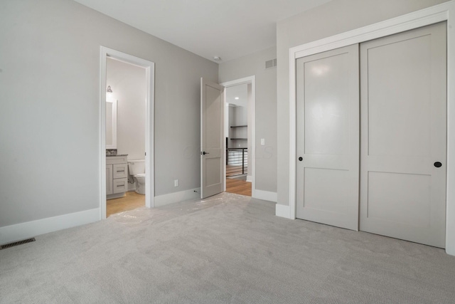 unfurnished bedroom with light colored carpet, a closet, and visible vents