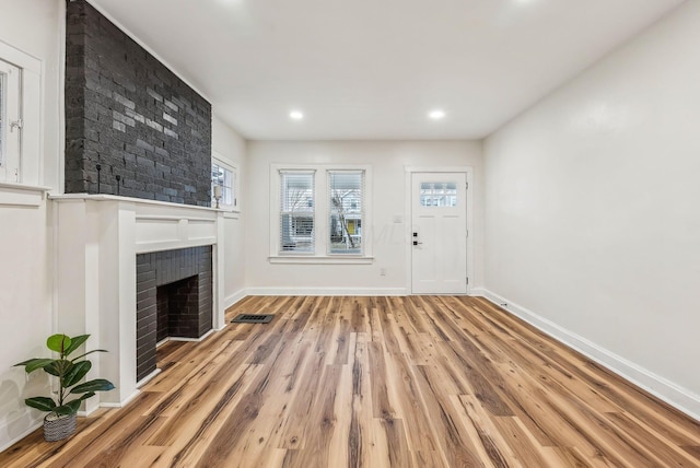 unfurnished living room with recessed lighting, visible vents, baseboards, light wood-style floors, and a brick fireplace