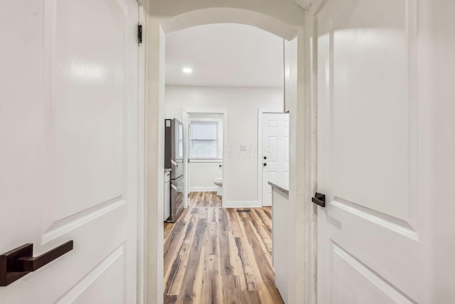 hall with arched walkways, light wood-style flooring, baseboards, and recessed lighting