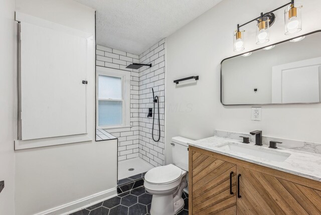 bathroom featuring tiled shower, a textured ceiling, toilet, and vanity