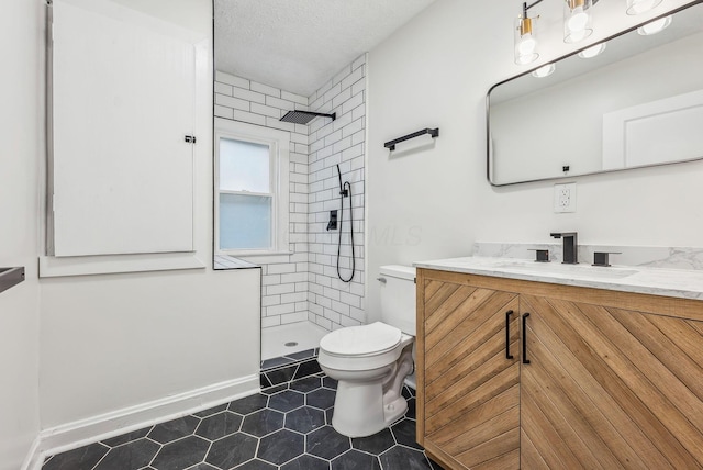 full bath with a textured ceiling, vanity, a tile shower, and toilet