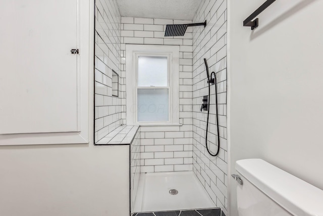 full bath featuring toilet, a textured ceiling, and tiled shower