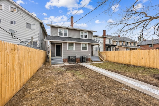 back of property with fence private yard, entry steps, a chimney, and central AC unit