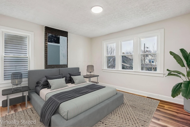 bedroom featuring a textured ceiling, wood finished floors, and baseboards