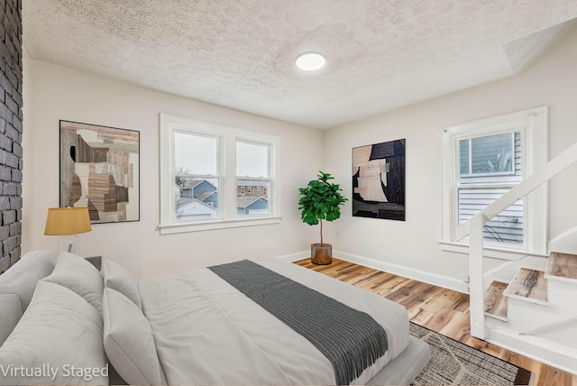 bedroom featuring a textured ceiling, baseboards, and wood finished floors