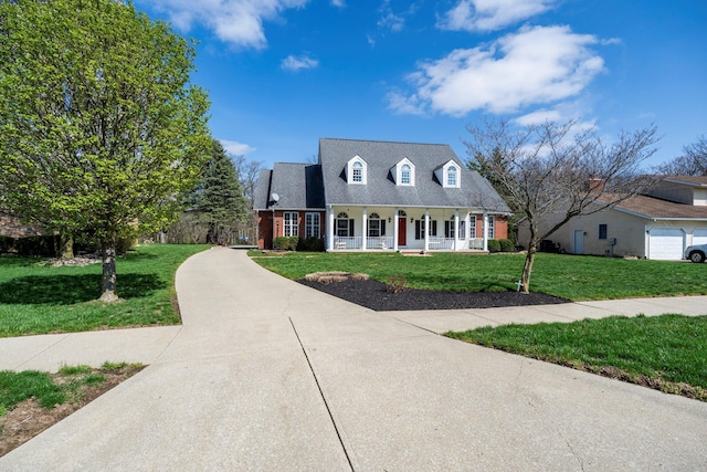 new england style home featuring driveway, a front yard, and a porch