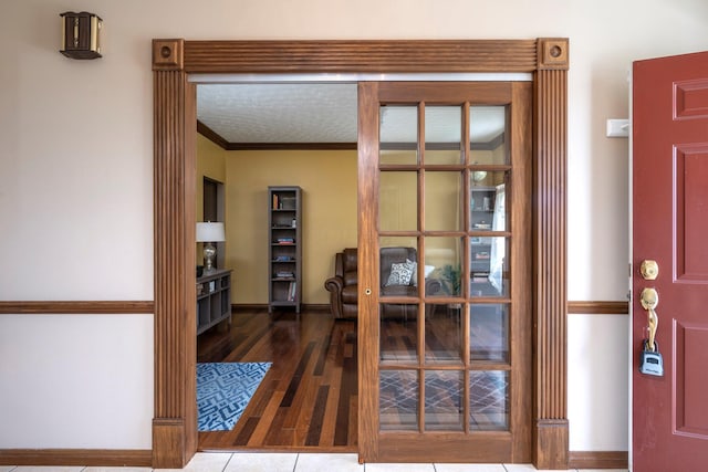 interior space featuring french doors, ornamental molding, baseboards, and wood finished floors