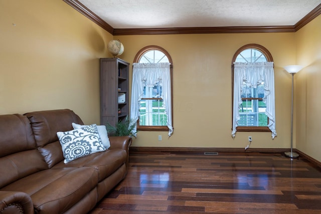 living area with baseboards, wood finished floors, ornamental molding, and a textured ceiling