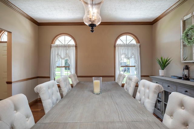 dining area with baseboards, wood finished floors, ornamental molding, and a textured ceiling