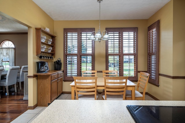 dining room with light tile patterned flooring, a textured ceiling, baseboards, and a chandelier