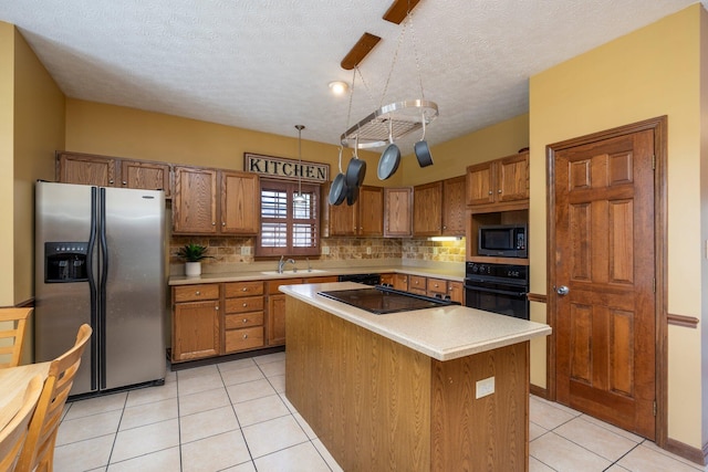 kitchen featuring light countertops, a sink, brown cabinetry, and black appliances