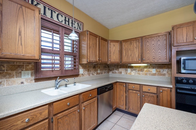 kitchen featuring light countertops, a sink, stainless steel appliances, and brown cabinetry