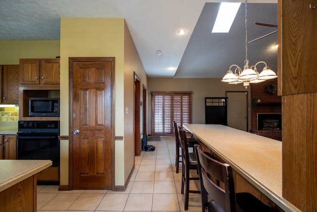 kitchen featuring light countertops, brown cabinetry, an inviting chandelier, light tile patterned floors, and oven