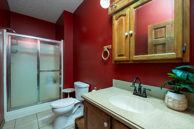 full bath featuring a stall shower, toilet, vanity, a textured ceiling, and tile patterned flooring