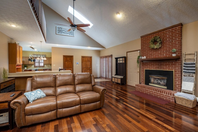 living area with a textured ceiling, a skylight, ceiling fan, a fireplace, and wood finished floors
