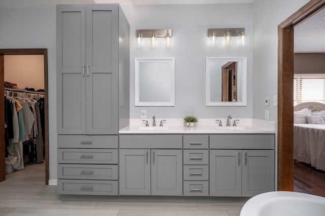 full bath featuring double vanity, ensuite bath, and a sink