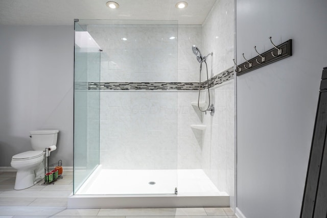 bathroom featuring baseboards, a tile shower, and toilet