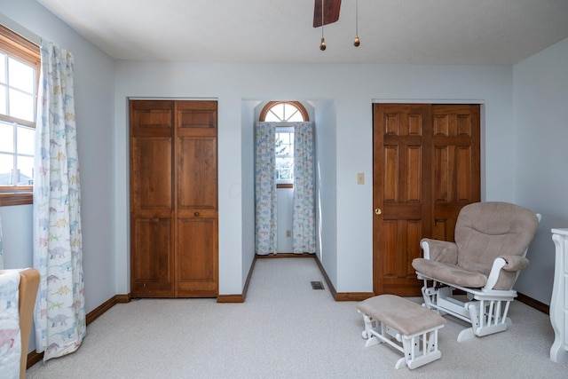 sitting room with a ceiling fan, baseboards, light colored carpet, and visible vents