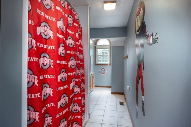 full bath featuring a textured ceiling, visible vents, baseboards, tile patterned floors, and a shower with curtain