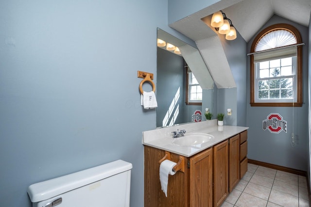 bathroom featuring baseboards, toilet, vanity, vaulted ceiling, and tile patterned flooring