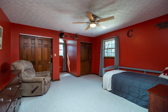 carpeted bedroom featuring baseboards, a textured ceiling, and multiple windows