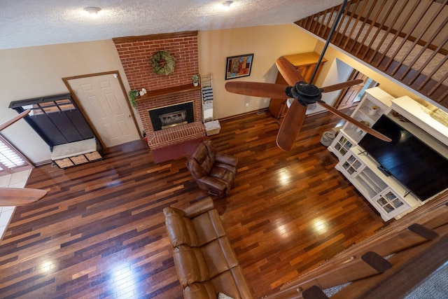 living room featuring a textured ceiling, a fireplace, hardwood / wood-style flooring, and vaulted ceiling