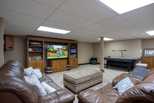 carpeted living area featuring baseboards and a drop ceiling