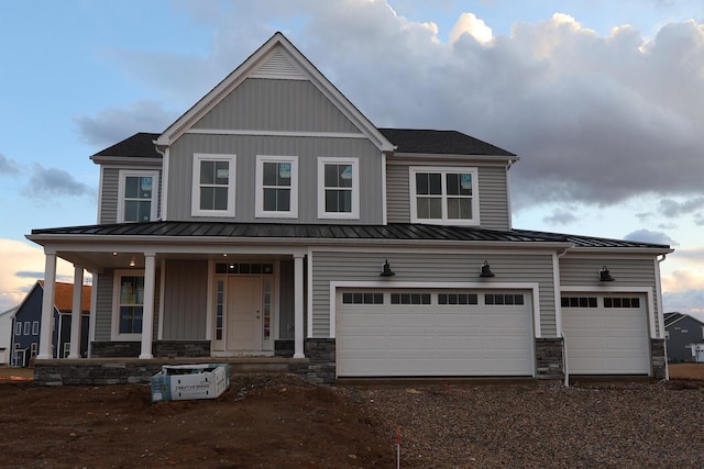 view of front of home featuring stone siding, dirt driveway, and a standing seam roof