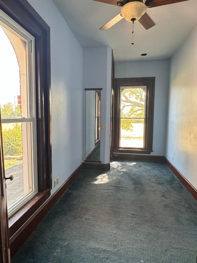 carpeted spare room with a ceiling fan and baseboards